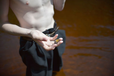 Midsection of man holding while standing by water