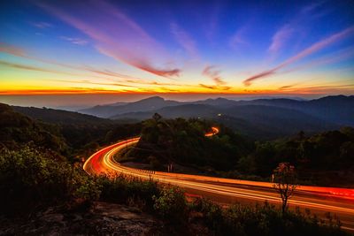 Light trails on road against sky at sunset