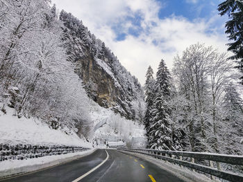 Road by snowcapped mountains against sky during winter