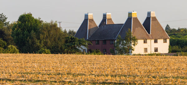 House on field by trees against sky