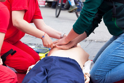 Midsection of instructor teaching paramedic while performing cpr on dummy