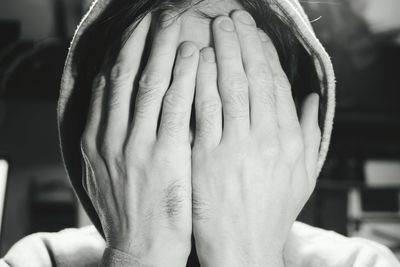 Close-up of person with face covered by hands