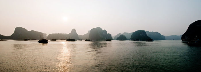 Scenic view of sea and silhouette mountains against clear sky