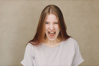 Portrait of young woman standing against wall