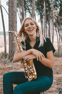 Portrait of smiling young woman sitting against trees