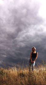 Low angle view of woman standing on field against cloudy sky