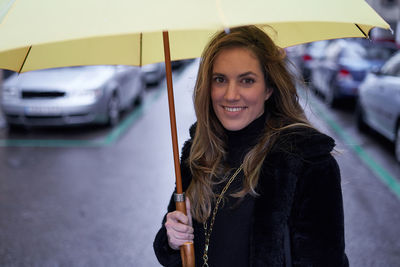 Pretty girl smiling on the street with a yellow umbrella, close-up