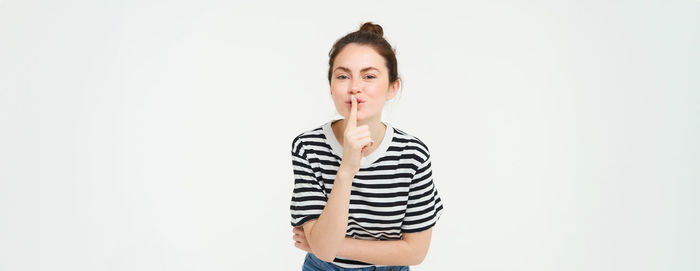 Portrait of young woman standing against white background