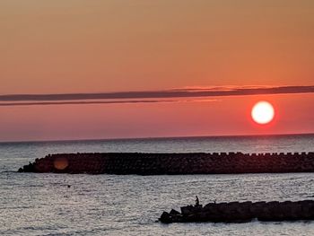 Scenic view of sea against orange sky