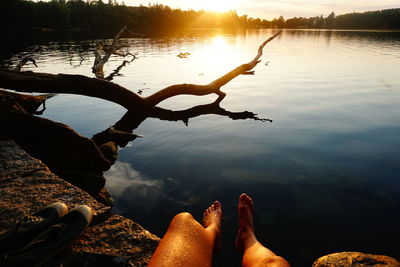 Low section of people by lake against sky