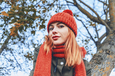 Autumn fashion portrait of stylish woman in bright orange knitted hat and scarf. playful look.