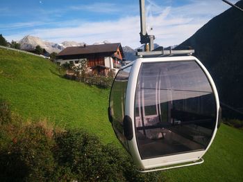 Car on field by houses against sky