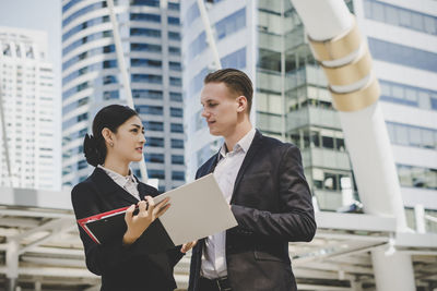 Low angle view of business people discussing while standing against building