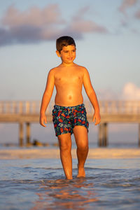 Cute kid walking on the beach at sunset