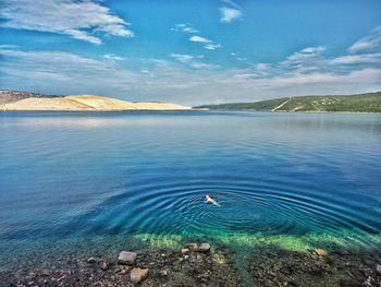 Man swimming in lake against sky