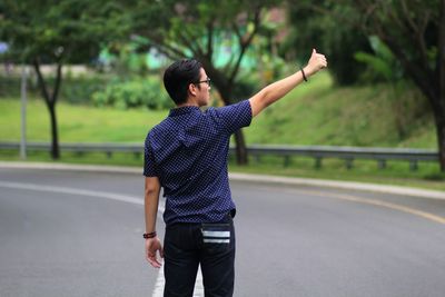 Man showing thumbs up while standing on road