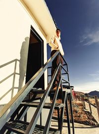 Low angle view of man standing on lifeguard hut at beach