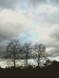 Low angle view of bare tree against cloudy sky