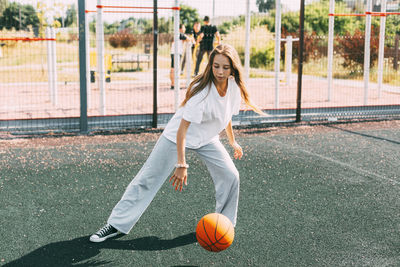 A teenage girl leads a basketball on a sports field, a girl protects the ball during a game