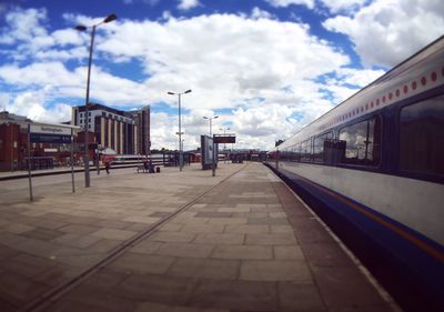 View of railroad station platform against cloudy sky