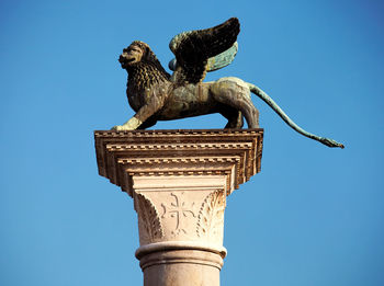 Statue of winged lion on column against clear blue sky at st mark square