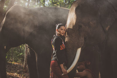 Portrait of smiling woman standing with elephant in temple