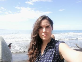 Portrait of beautiful young woman standing at beach