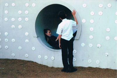 Rear view of man and woman standing against wall