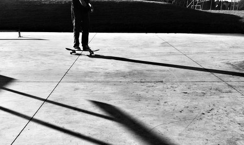 Low section of man skateboarding on walkway during sunny day