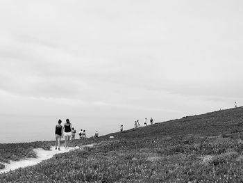 People walking on field against sky