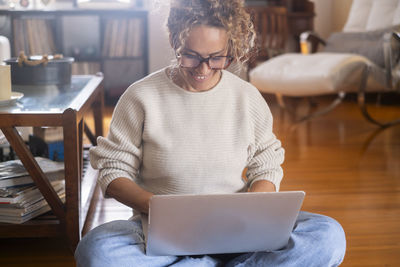 Young woman using digital tablet while sitting on table