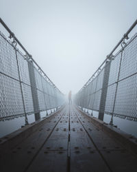 Man standing on footbridge against sky