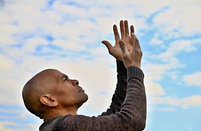 Low angle view of man gesturing against sky