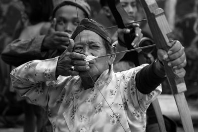 Man aiming through bow and arrow outdoors