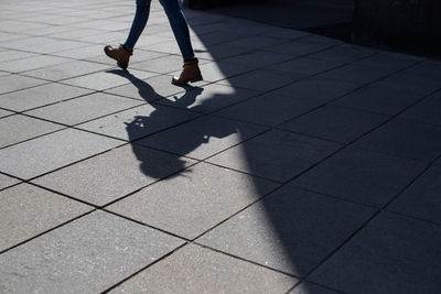 Low section of woman walking on footpath in city