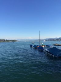 Boats in sea against clear sky