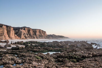 Rock formations by sea against clear sky