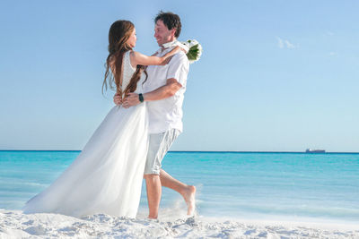 Newlyweds dancing on the beach.