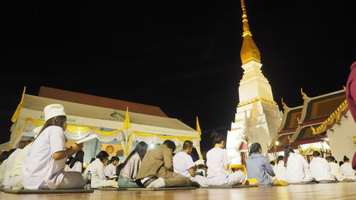 People at temple against building at night