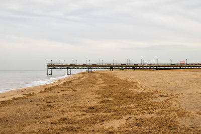 Pier on beach against sky