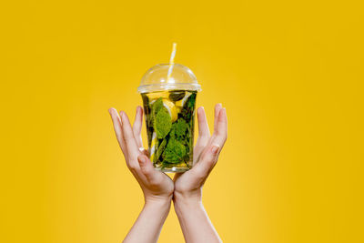 Woman holding drink against yellow background