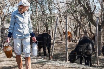 Woman holding milk in container standing at farm