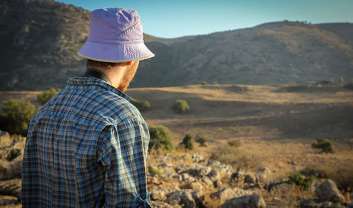 Rear view of man standing against mountain during sunset