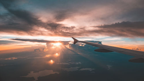 Airplane flying over cloudscape during sunset