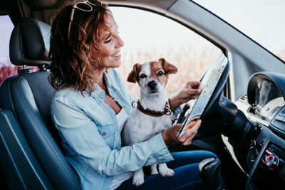 Woman with puppy analyzing map in camper trailer