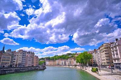 River amidst buildings in city against sky