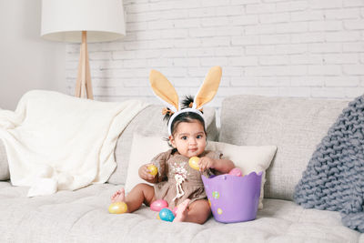 Portrait of cute baby girl sitting on sofa at home