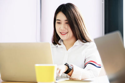 Portrait of a smiling young woman using phone