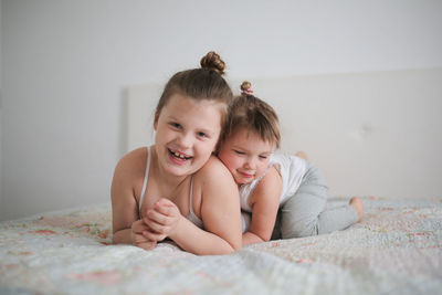 Sister girls play playfully on the bed, emotions. they swear and joke. concept childhood