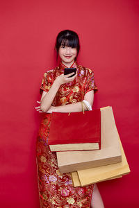 Portrait of a smiling young woman against red background